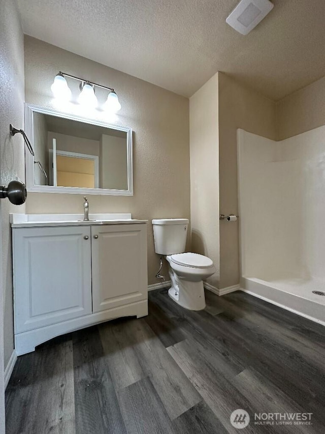 full bath featuring walk in shower, toilet, wood finished floors, and a textured ceiling