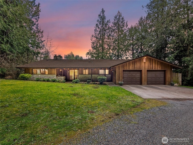 mid-century home featuring a lawn, a garage, driveway, and a chimney