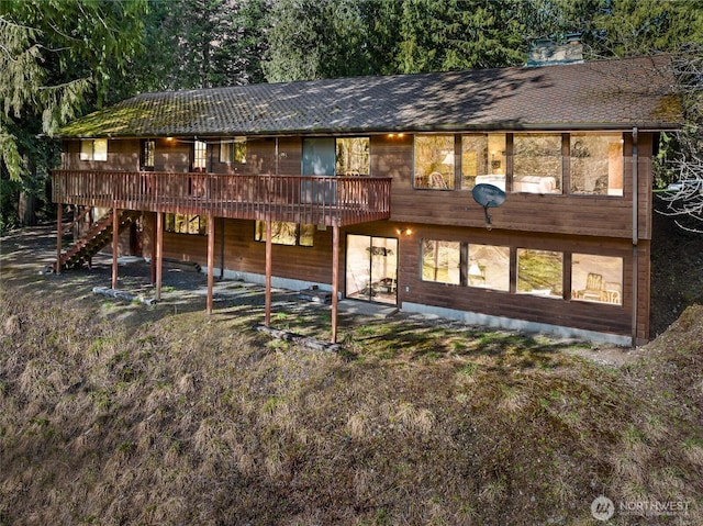 rear view of property featuring stairway, roof with shingles, and a deck