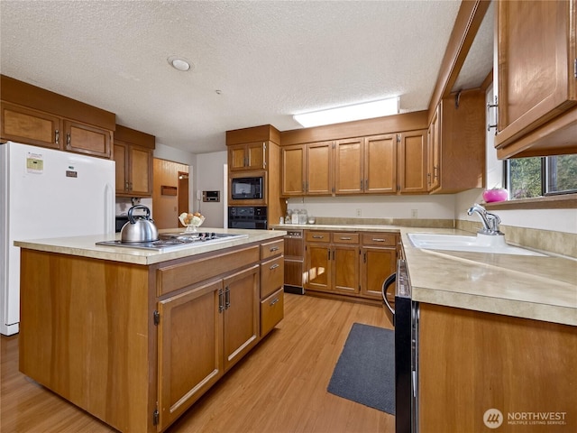 kitchen with a kitchen island, light wood-type flooring, light countertops, brown cabinetry, and black appliances