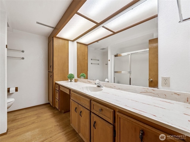 full bathroom featuring vanity, wood finished floors, baseboards, a shower stall, and toilet