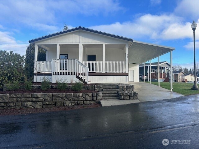 manufactured / mobile home featuring a carport, covered porch, and driveway