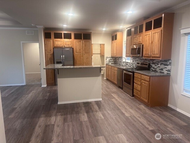 kitchen featuring dark wood-type flooring, ornamental molding, a sink, stainless steel appliances, and decorative backsplash