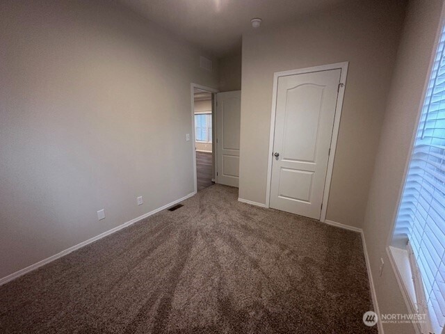 unfurnished bedroom with carpet flooring, visible vents, and baseboards