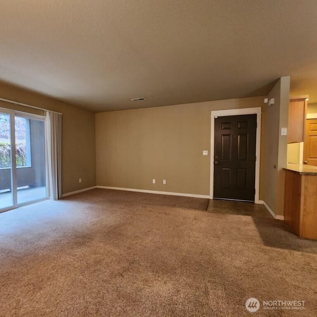 interior space featuring baseboards, carpet floors, a textured ceiling, and visible vents