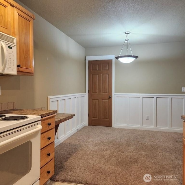 kitchen featuring white appliances, a decorative wall, light colored carpet, and a textured ceiling