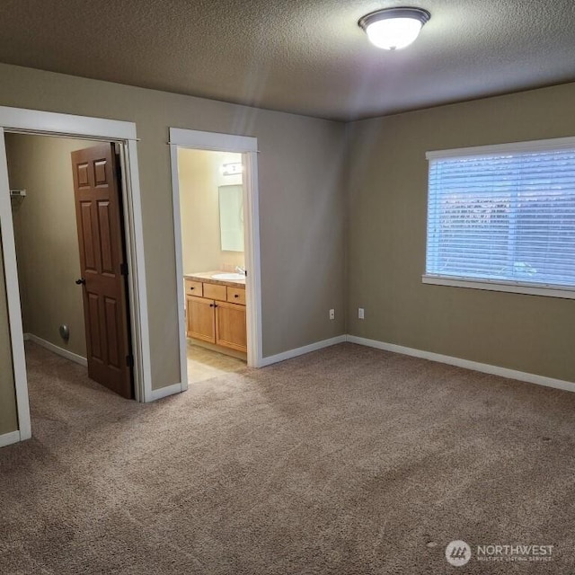 unfurnished bedroom with a textured ceiling, baseboards, and light carpet