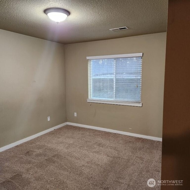 carpeted empty room with visible vents, baseboards, and a textured ceiling