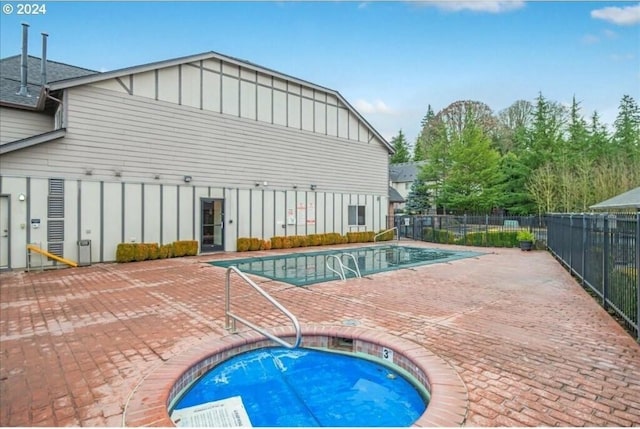 community pool featuring a patio, fence, and an in ground hot tub