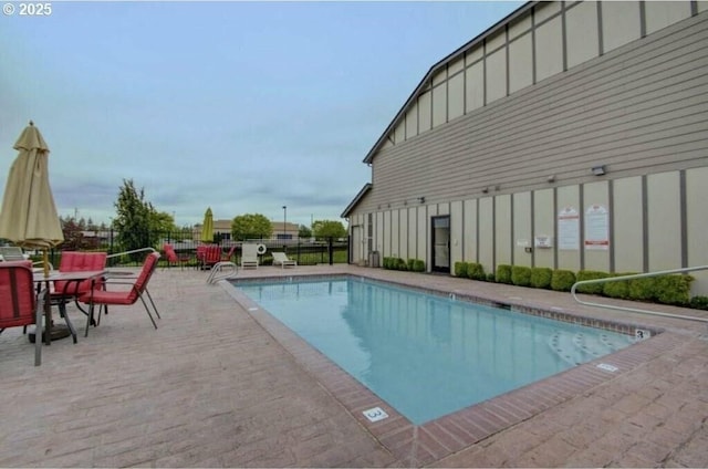 pool with a patio area and fence