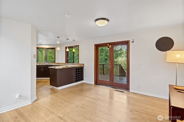 kitchen featuring visible vents, baseboards, light wood-style floors, and a peninsula