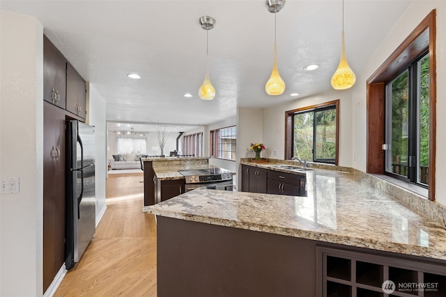 kitchen with light stone counters, recessed lighting, light wood-style flooring, a peninsula, and stainless steel appliances