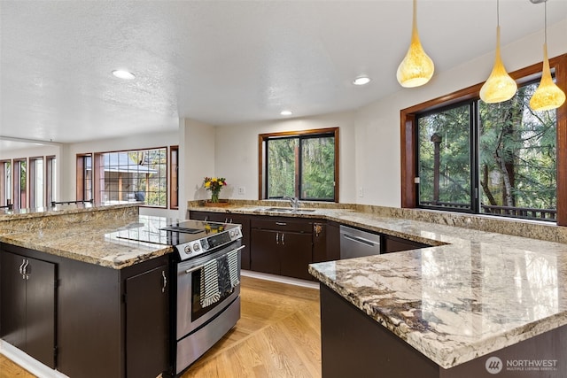 kitchen with light stone countertops, recessed lighting, appliances with stainless steel finishes, a textured ceiling, and a sink