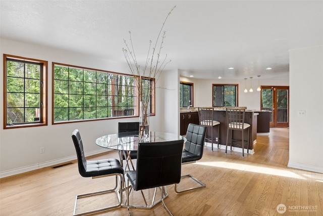 dining space featuring a wealth of natural light, visible vents, baseboards, and light wood-style floors