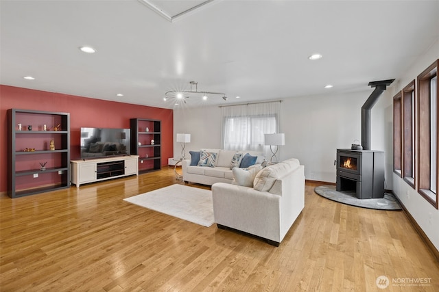 living room with recessed lighting, light wood-type flooring, baseboards, and a wood stove