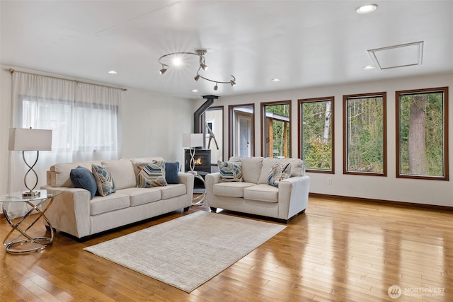 living room with a wood stove, recessed lighting, light wood-style floors, and baseboards