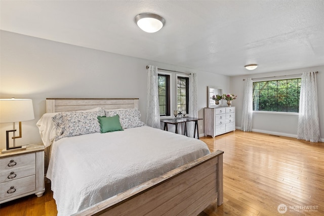 bedroom featuring visible vents, baseboards, and hardwood / wood-style flooring