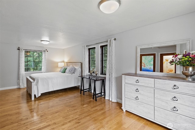 bedroom featuring light wood finished floors and baseboards