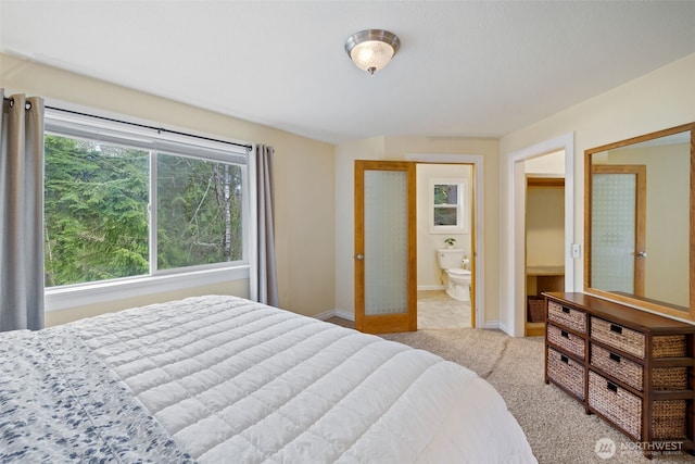 bedroom with ensuite bath, carpet flooring, and baseboards