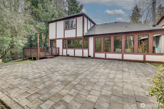 back of house featuring a shingled roof, a deck, a patio area, and stucco siding