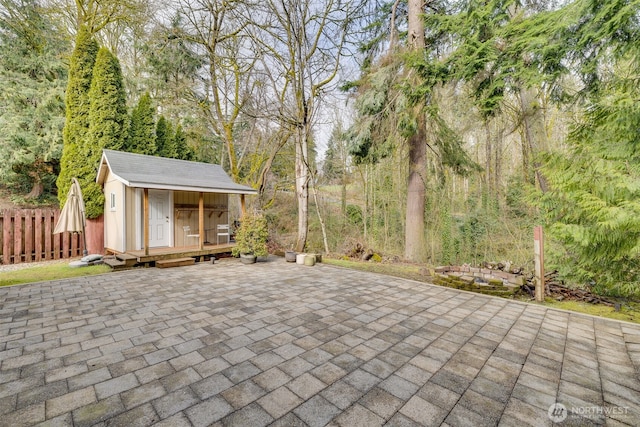 view of patio featuring a storage unit, an outbuilding, and fence