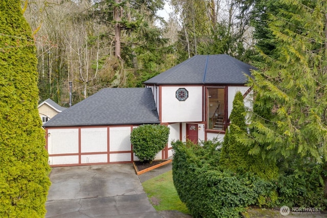 view of front of home featuring stucco siding, a garage, roof with shingles, and driveway