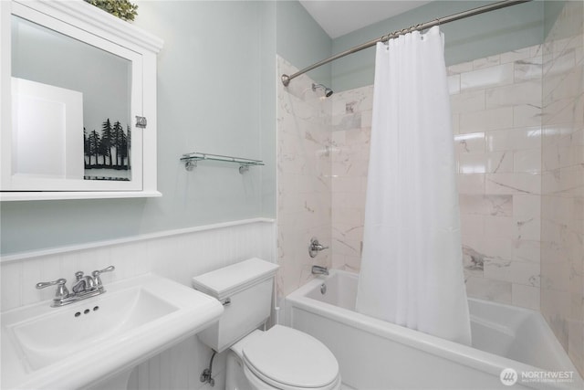 full bath featuring a sink, a wainscoted wall, toilet, and shower / bath combo