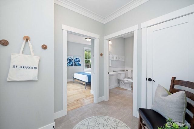 hallway with light tile patterned floors, crown molding, and baseboards