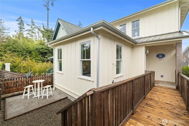 view of side of home with a shingled roof, fence, metal roof, a patio area, and a standing seam roof