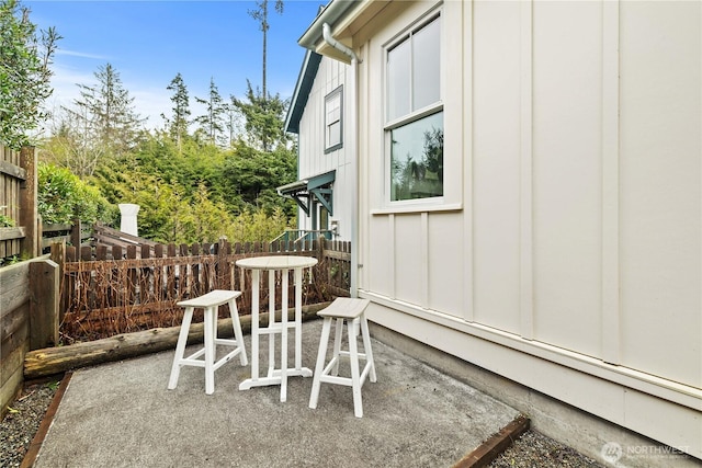 view of property exterior featuring a patio area, fence, and board and batten siding