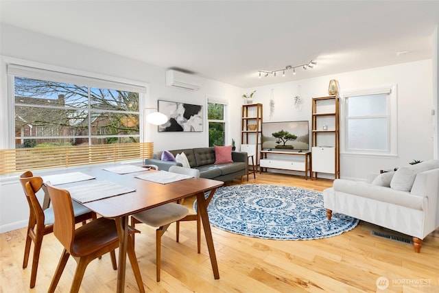 living room with light wood finished floors and a wall unit AC