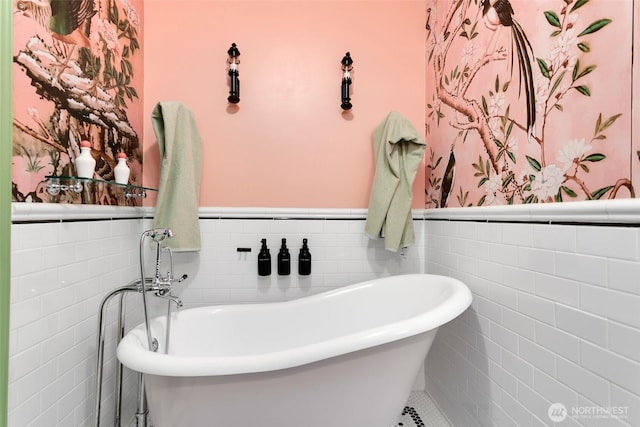 bathroom with a wainscoted wall, a freestanding bath, and wallpapered walls