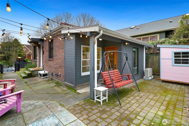 exterior space featuring brick siding, a patio, central AC unit, and fence