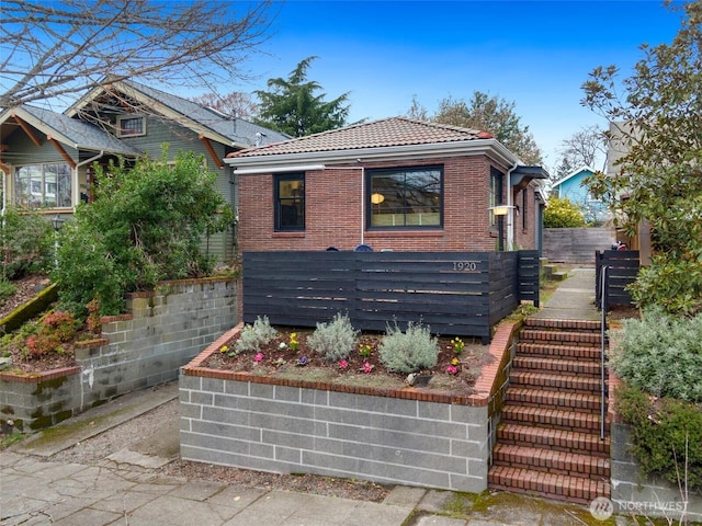 view of front of home with stairway, brick siding, and a tile roof