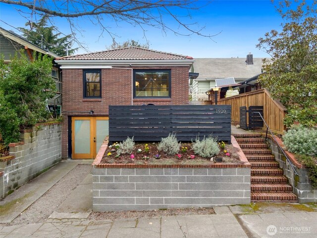 view of front facade with stairway, fence, brick siding, and a tiled roof