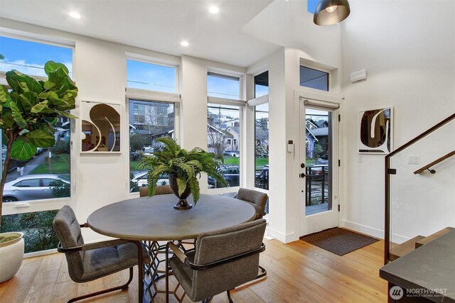 dining space with a towering ceiling, recessed lighting, baseboards, and wood finished floors