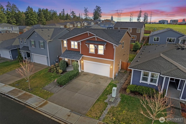 traditional home featuring a garage, a residential view, driveway, and fence