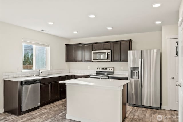 kitchen featuring dark brown cabinets, light wood-style floors, appliances with stainless steel finishes, and a sink