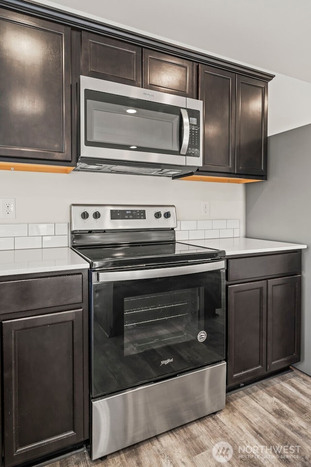 kitchen with dark brown cabinetry, appliances with stainless steel finishes, light countertops, and light wood-type flooring