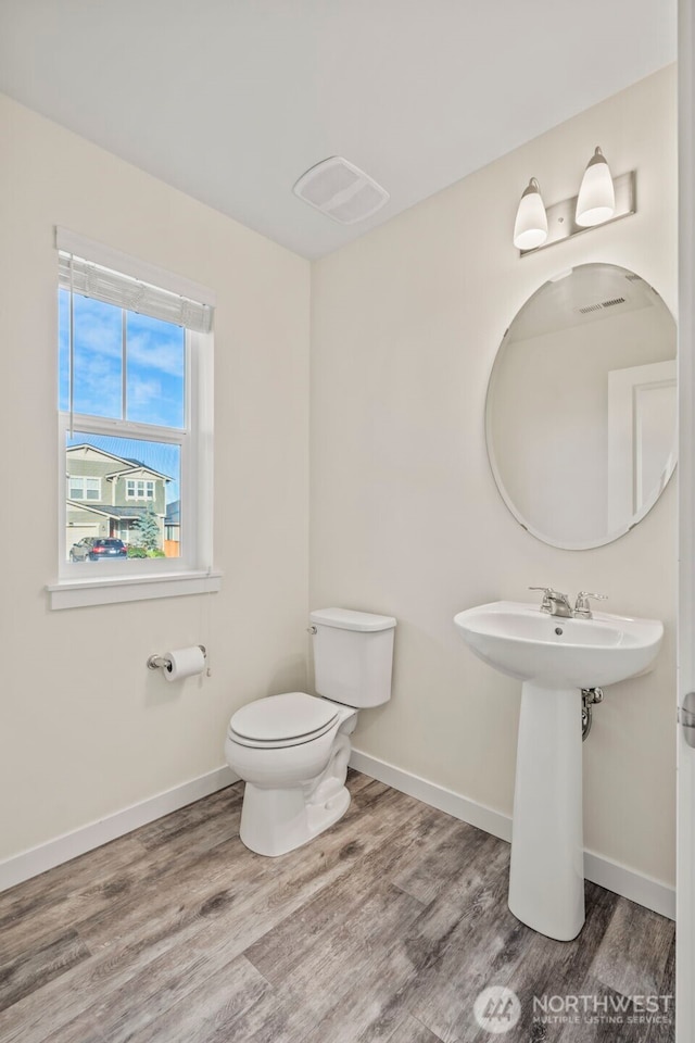 half bathroom featuring visible vents, toilet, baseboards, and wood finished floors