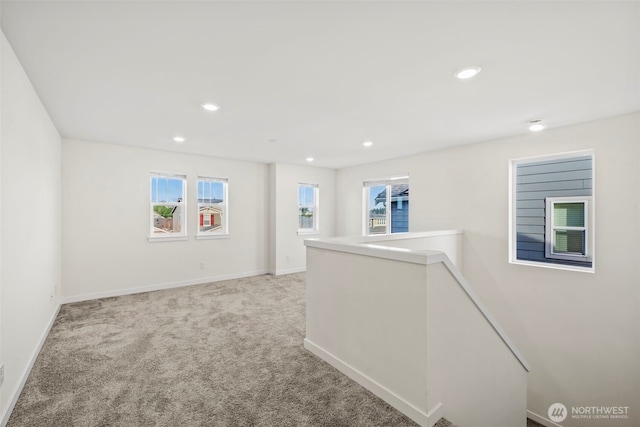 corridor featuring recessed lighting, baseboards, an upstairs landing, and light carpet