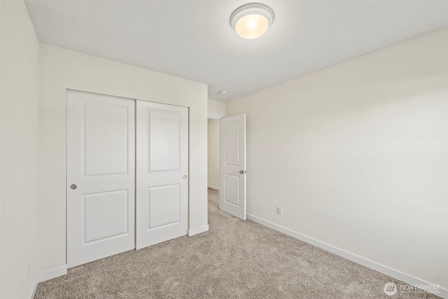 unfurnished bedroom featuring a closet, baseboards, and carpet