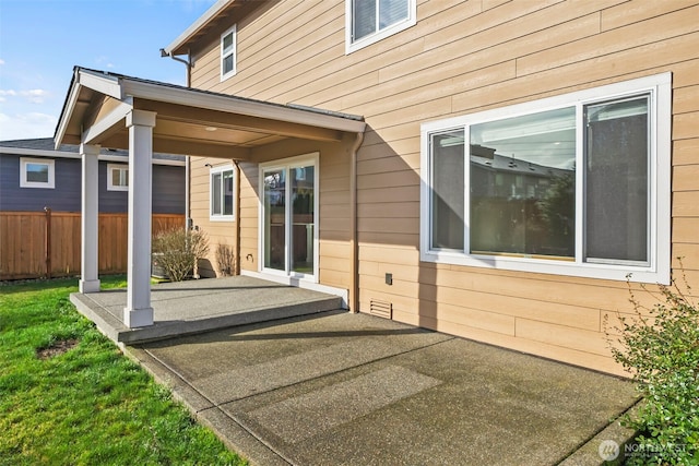 doorway to property featuring a patio, a lawn, and fence