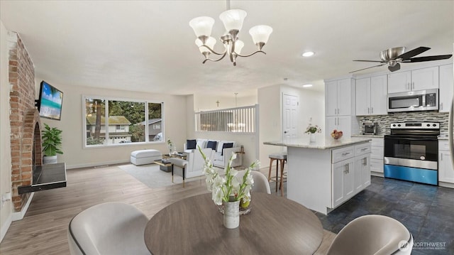 dining area with dark wood finished floors, recessed lighting, ceiling fan with notable chandelier, and baseboards