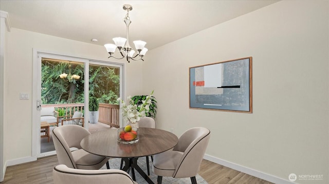 dining space featuring light wood-type flooring, baseboards, and a chandelier