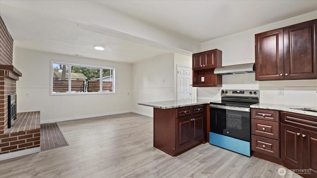 kitchen featuring a brick fireplace, under cabinet range hood, stainless steel electric stove, light wood-style flooring, and a peninsula