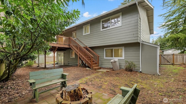 back of house featuring a deck, a patio, a fenced backyard, and stairs