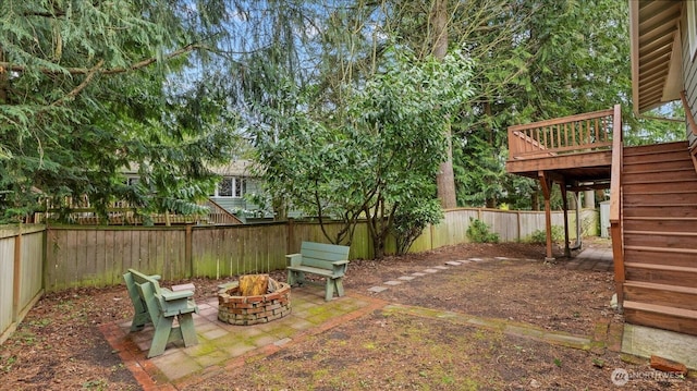 view of yard featuring a deck, a fire pit, and a fenced backyard