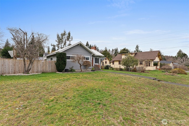 exterior space featuring entry steps, a chimney, a front lawn, and fence