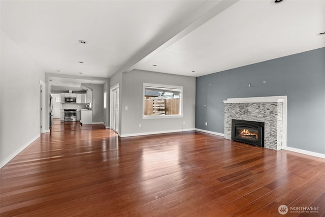 unfurnished living room with a glass covered fireplace, baseboards, and wood finished floors